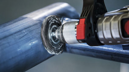 Slipmaskin slipar en metallrörs yta med roterande borste.