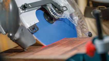 Cirkelsåg med blått blad kapar ett trägolvbräde.