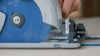 Cirkelsåg med blå klinga och silverfärgat hölje som skär genom material. En hand greppar verktyget.