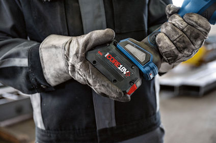 En person i arbetshandskar håller en blå Bosch 18V-borrmaskin.