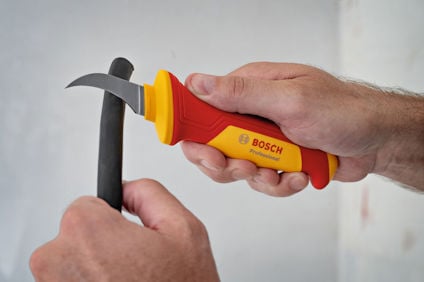 Hand håller en Bosch Professional kabelskalare mot en kabel.