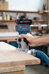 En hand håller i en Bosch Professional handöverfräs med ett blått batteri och kopplat sugslang, bearbetar en träyta.