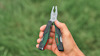 Hand som håller en grön och svart multiverktygstång mot en grön bakgrund.