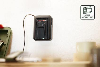 Batteriladdare monterad på vit vägg, ansluten till eluttag. Text: "WALL MOUNTING".
