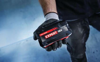 Hand i handske håller i ett batteri märkt "EXPERT 18V".