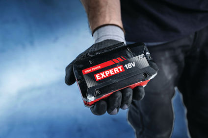 En person i svarta kläder och handskar håller ett 18V Expert batteri märkt "High Power".