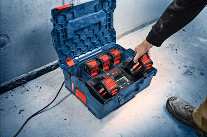 Öppen verktygsväska med laddstation och tre batterier, person laddar ett batteri, blå och röda detaljer.