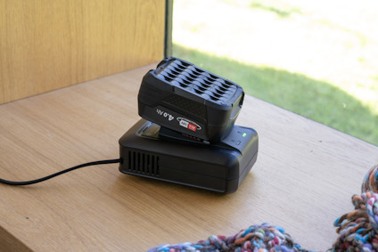 Batteriladdare med ett anslutet batteri på ett bord vid ett fönster.