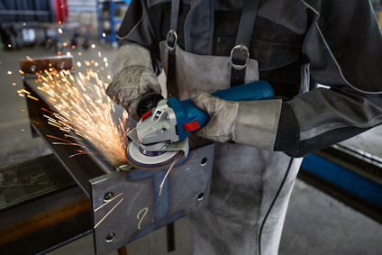 Person som använder en vinkelslip på ett metallstycke, gnistor flyger.