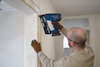 Person använder spikpistol för att fästa lister runt en dörrkarm inomhus.