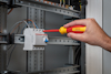 Hand som använder en Bosch-skruvmejsel för att arbeta på en elektrisk brytare i ett elskåp.