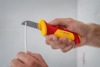 Hand håller en Bosch-kniv med gul och röd handtag, skär en vit kabel.