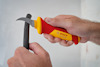 Två händer håller en kniv och ett grått rör. Handtaget på kniven är röd-gult med texten "BOSCH Professional".