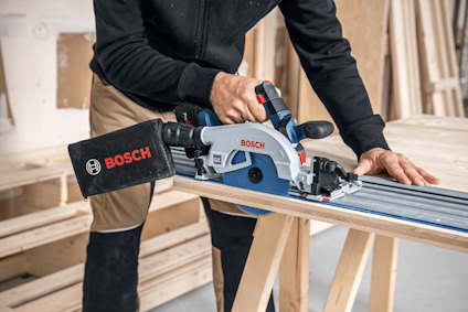 En person använder en Bosch cirkelsåg med en styrskena på träbrädor.