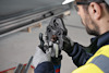 Person i arbetskläder använder en elektrisk presstång för att bearbeta ett metallrör.