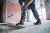 Person använder en stor borrmaskin för att bryta upp betonggolv i en byggarbetsplats.