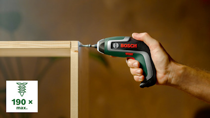 En hand håller en Bosch lättviktsborrmaskin medan den skruvar i en träkonstruktion. Text: "190 x max.".