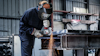 Person i skyddsutrustning slipar metall i en industrimiljö, gnistor flyger.