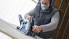 Person with goggles and mask using a circular saw on a wooden board.
