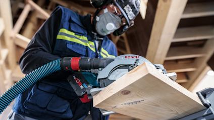 Person med skyddsutrustning sågar trä med en Bosch cirkelsåg.