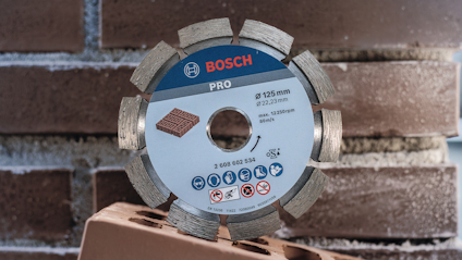 Diamantskiva märkt "Bosch Pro" 125 mm, framför en stapel tegelstenar.
