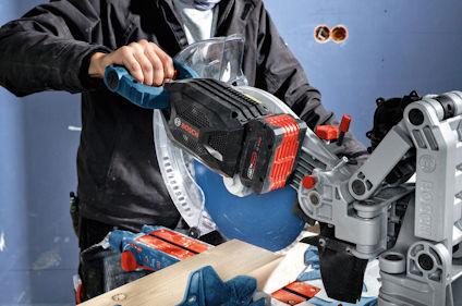 En person använder en Bosch kap- och geringssåg som bearbetar trä.