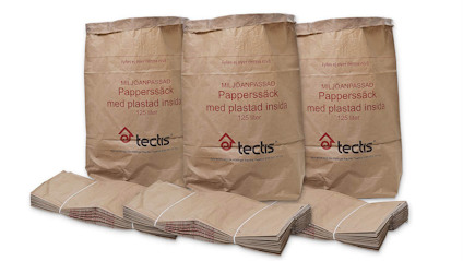 Tre bruna papperssäckar med texten "Miljöanpassad Papperssäck med plastad insida 125 liter" staplade framför vikt kartong.