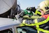Räddningsarbetare använder en grön batteridriven såg för att skära en bils tak.