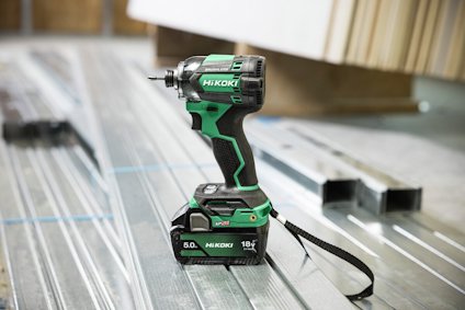 Sladdlös skruvdragare med gröna detaljer märkt "Hikoki" placerad på metallbalkar.