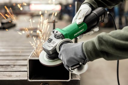 Vinkelslip används för att slipa metall, gnistor flyger. Två händer med handskar håller verktyget.