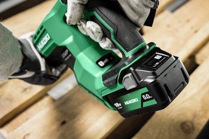 Grön och svart batteridriven elverktyg med handtag. Märke: Hikoki. Handske håller i verktyget.