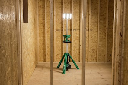 Stativmonterad arbetslampa med fyra lysrör i plywoodklädd byggnadsställning.