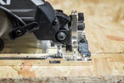 Cirkelsåg skär genom plywood med synliga sågspån.