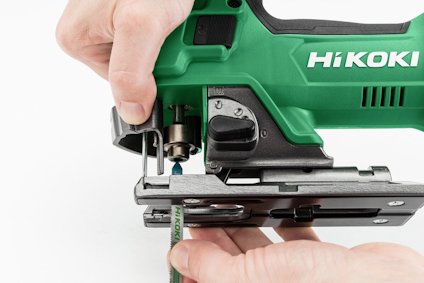 Grön HiKOKI sticksåg med användarens händer som justerar bladet.