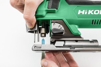 Grön sticksåg med texten "HiKOKI" synlig. Händer justerar bladskenan.