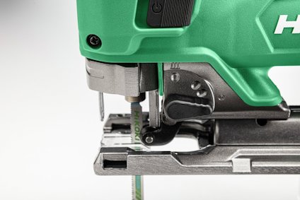 Grön elektrisk sticksåg med metallbas och sågklinga i nederkant.
