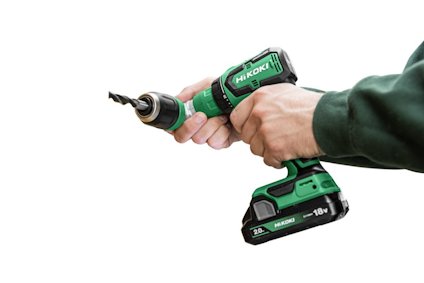 Person håller en grön och svart Hikoki borrmaskin med ett batteri märkt "18V".