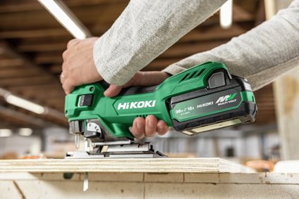 Grön batteridriven HIKOKI sticksåg i användning på en träyta.