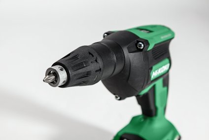 Grön och svart batteridriven borrmaskin med metallborr monterad i chucken.