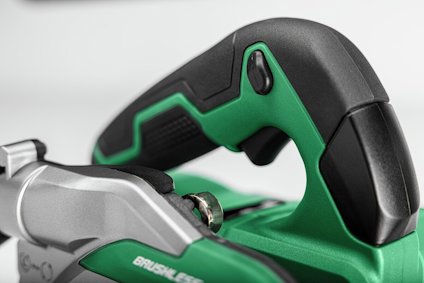 Grön och svart handtag av ett elektriskt verktyg med en knapp, del av en såg eller liknande utrustning.