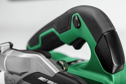 Svart och grön handtag på en elektrisk verktyg med grå delar, fokus på handtaget.