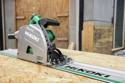 En cirkelsåg märkt "Hikoki" placerad på en skena ovanpå en plywoodskiva utomhus.