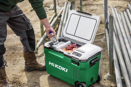 Grön HiKOKI kylbox med öppen lucka. Inuti finns frukt och vattenflaska. En person når ner till boxen, omgiven av metallstänger.