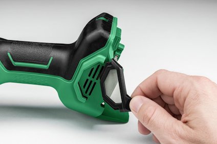 Hand sätter fast ett svart filter på en grön och svart elektrisk verktygsdel.