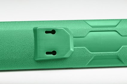 Grön plastskiva med textur och två ovala hål monterade på en ram.