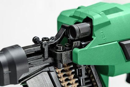 Grön och svart spikpistol med spikmagasin synligt och justeringsknopp i närbild.