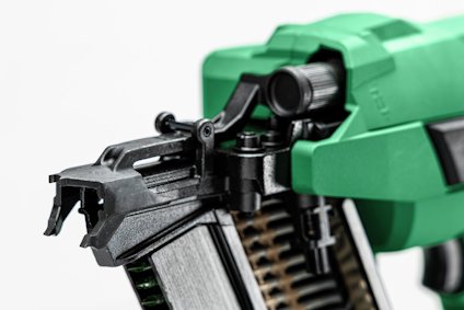 Grön spikpistol med metallmagasin, sedd från sidan.