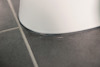 Vitt porslin på grått klinkergolv med mörka fogar.