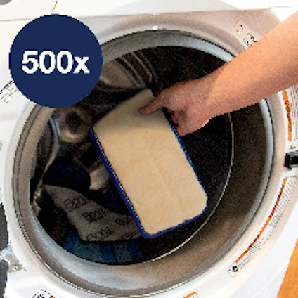 En hand sätter in en beige rektangulär kudde i en tvättmaskin. En cirkel med texten "500x" syns.