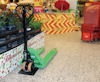 Grön handtruck på butiksgolv, omgiven av skyltar med erbjudanden och staplade varukorgar.